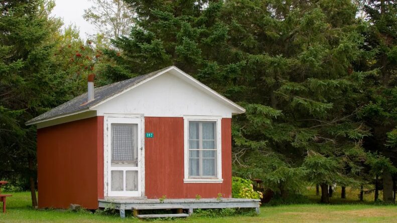 a small red house sitting in the middle of a grassy field