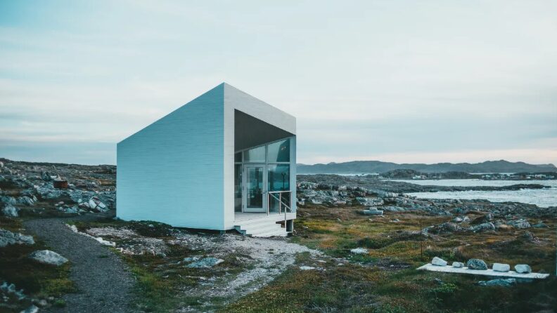 a tiny white house sitting on top of a rocky hill