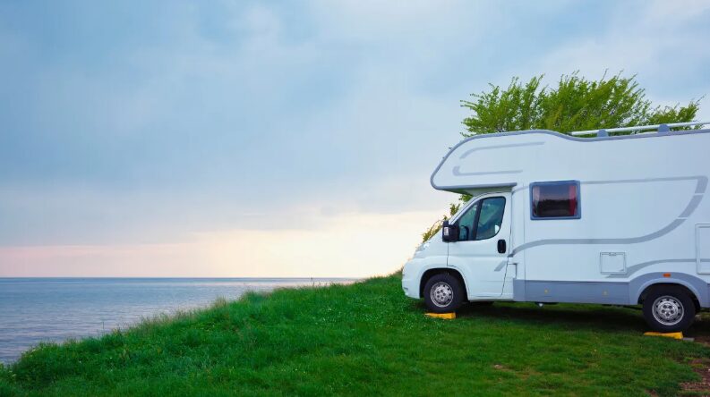 an rv parked on the side of the road near the ocean